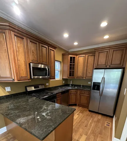 a kitchen with stainless steel appliances granite countertop a refrigerator a stove a sink a washer dryer and a refrigerator