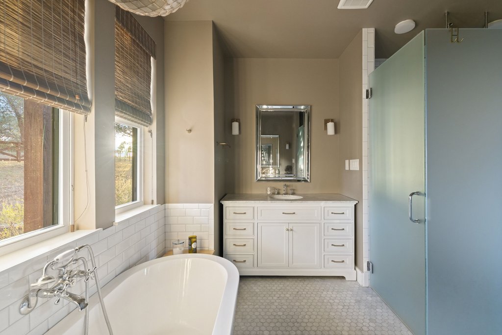 32045 Mirela Ann Road Dripping Springs, TX 78620 - Photo 17 of 30 A freestanding tub and tiled vanity area create a relaxing bathroom oasis with natural light.