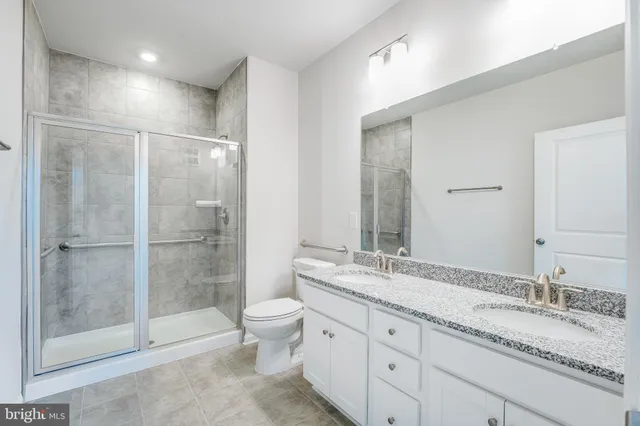 a bathroom with a granite countertop sink toilet mirror and shower