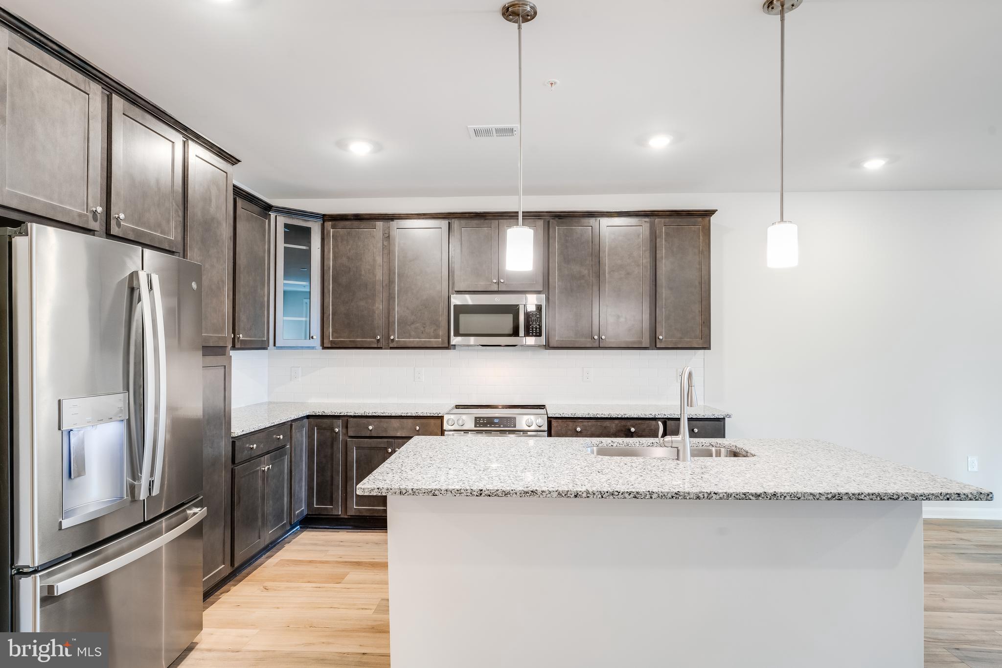 4003 Seaside Alder Road, Unit 201 ROSE Bowie, MD 20720 - Photo 5 of 16 a kitchen with kitchen island granite countertop stainless steel appliances a sink stove refrigerator and cabinets