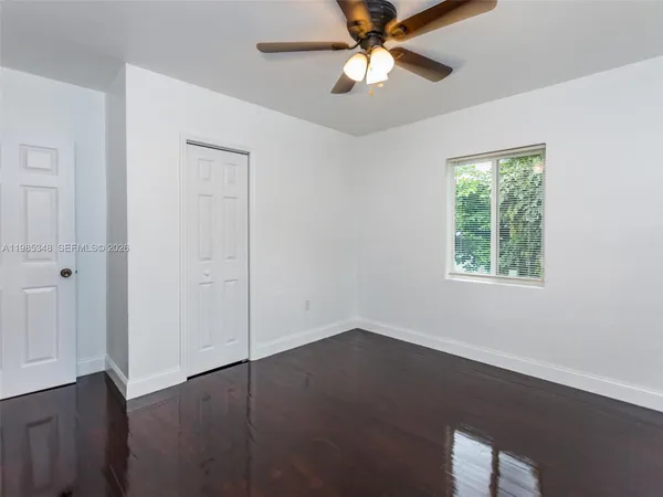 an empty room with a window and a fan
