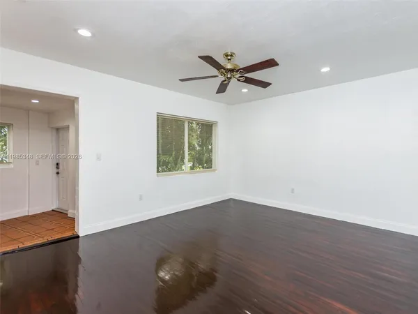 an empty room with wooden floor fan and windows
