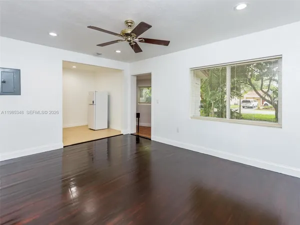 a view of empty room with wooden floor and fan