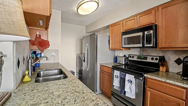 a kitchen with stainless steel appliances granite countertop a stove refrigerator and microwave