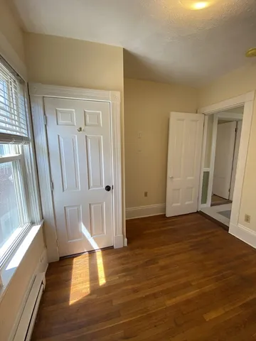 a view of empty room with wooden floor and window