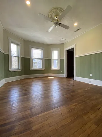 a view of an empty room with window and wooden floor