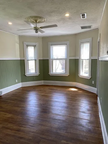 an empty room with wooden floor and windows with curtains view