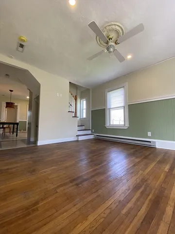 an empty room with wooden floor fan and windows