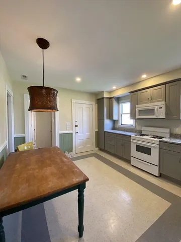 a kitchen with stainless steel appliances granite countertop a refrigerator a sink dishwasher a stove with white cabinets and wooden floor