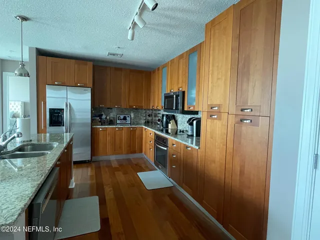a kitchen with kitchen island granite countertop a sink a counter top space appliances and cabinets