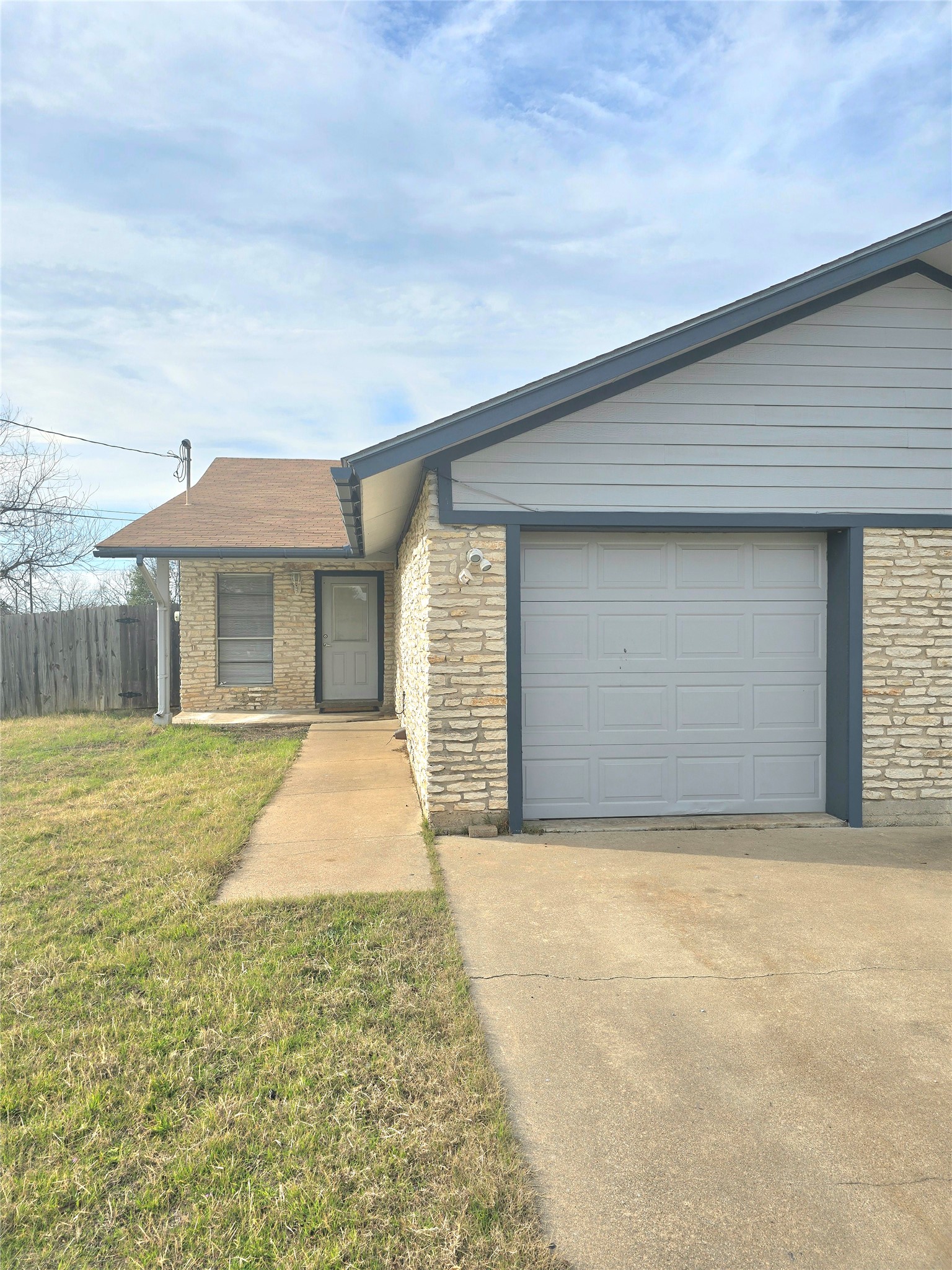 15208 Spring Hill Lane, Unit A Pflugerville, TX 78660 - Photo 2 of 16 Brick and siding exterior featuring a single-car garage with a panel door