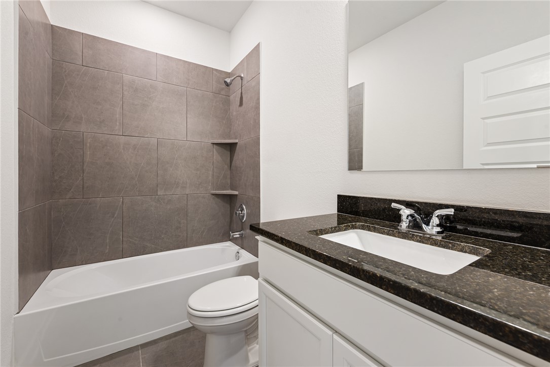 2415 Rooke Road Bryan, TX 77807 - Photo 9 of 36 a bathroom with a granite countertop sink a toilet a mirror and bathtub