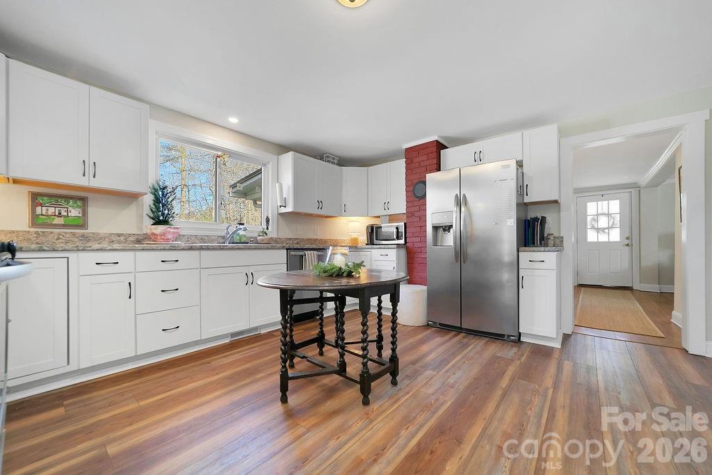 50 Illahee Point Brevard, NC 28712 - Photo 16 of 37 a kitchen with stainless steel appliances a refrigerator a sink dishwasher a stove and white cabinets with wooden floor