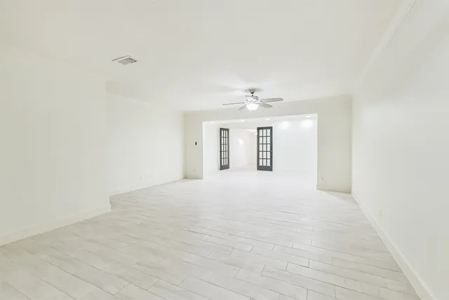 a view of an empty room with a chandelier fan