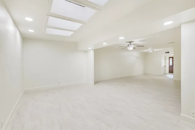 an empty room with white walls and chandelier fan