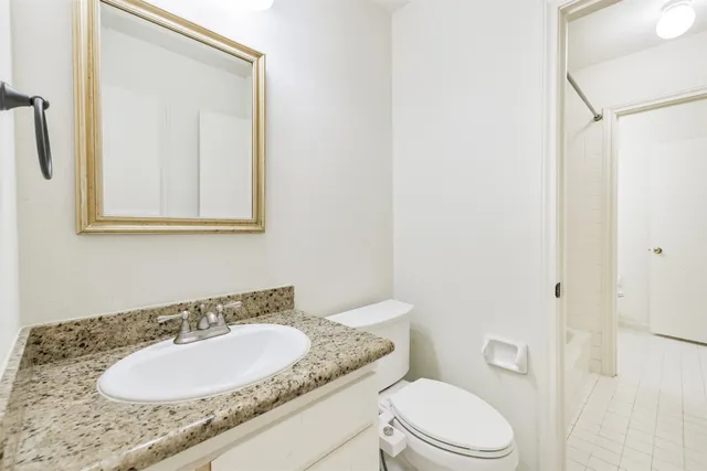 a bathroom with a granite countertop sink toilet a mirror and shower