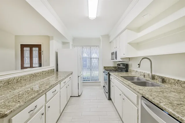 a large kitchen with granite countertop a sink and cabinets