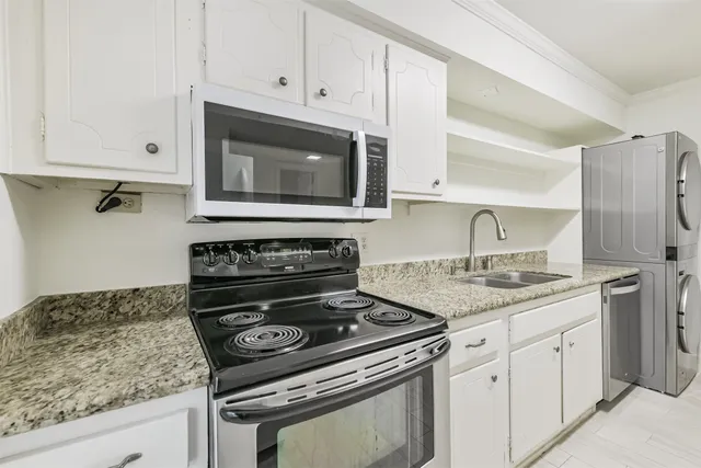a kitchen with granite countertop white cabinets and a stove top oven