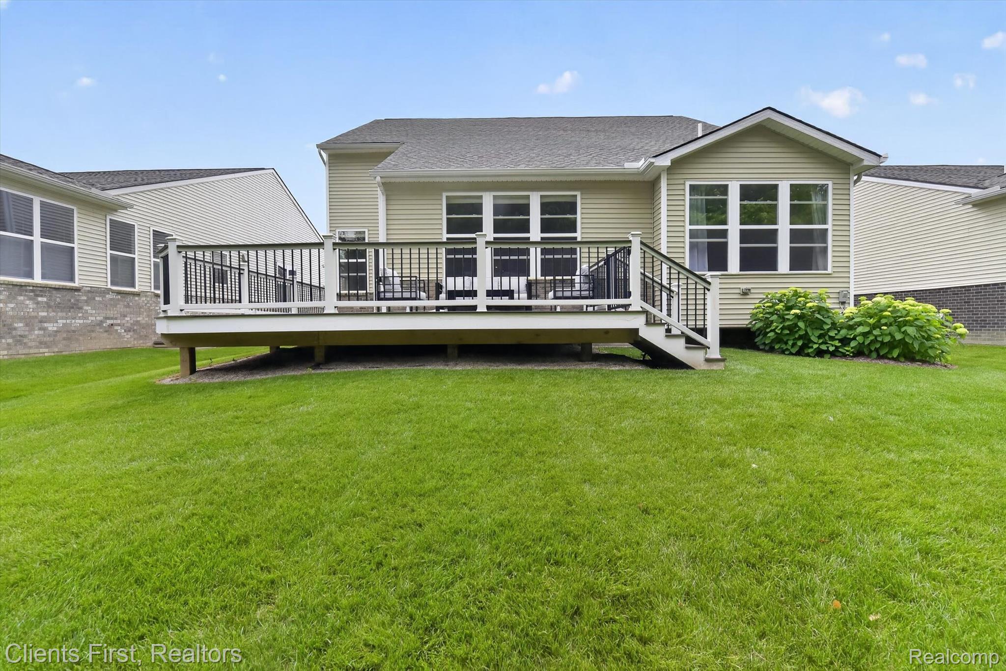 4699 Bingham Road Canton, MI 48188 - Photo 42 of 47 Expansive rear lawn featuring a raised deck with white railings and black balusters, exterior siding, and a sunroom extension