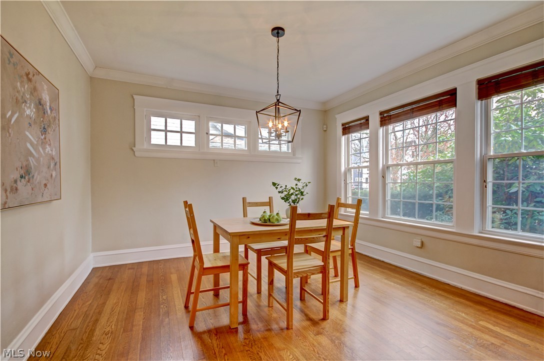 3054 Somerton Road Cleveland, OH 44118 - Photo 14 of 40 Dining area featuring a wealth of natural light, ornamental molding, light hardwood / wood-style floors, and a notable chandelier