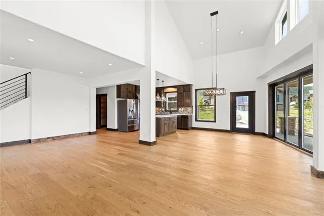 a view of an empty room with window and kitchen view