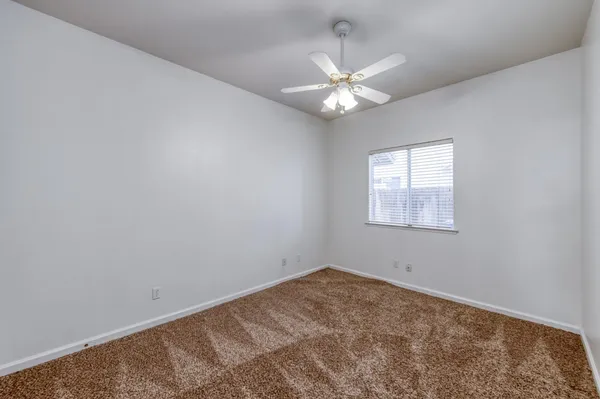 an empty room with a window and ceiling fan