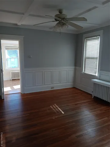 an empty room with wooden floor fan and windows