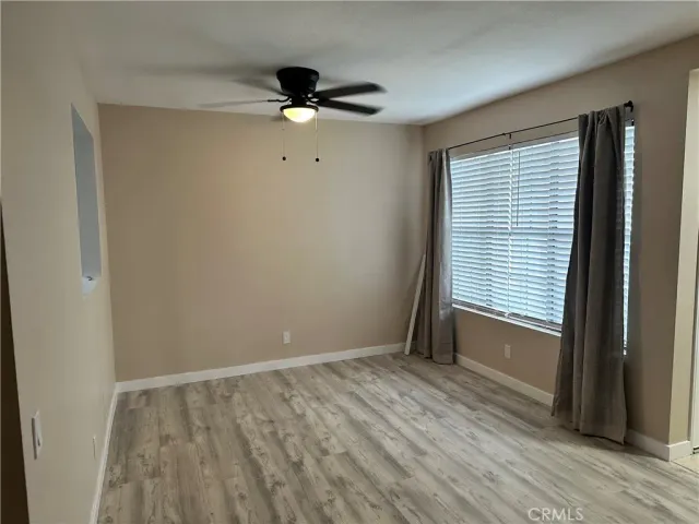 a view of an empty room with a window and wooden floor