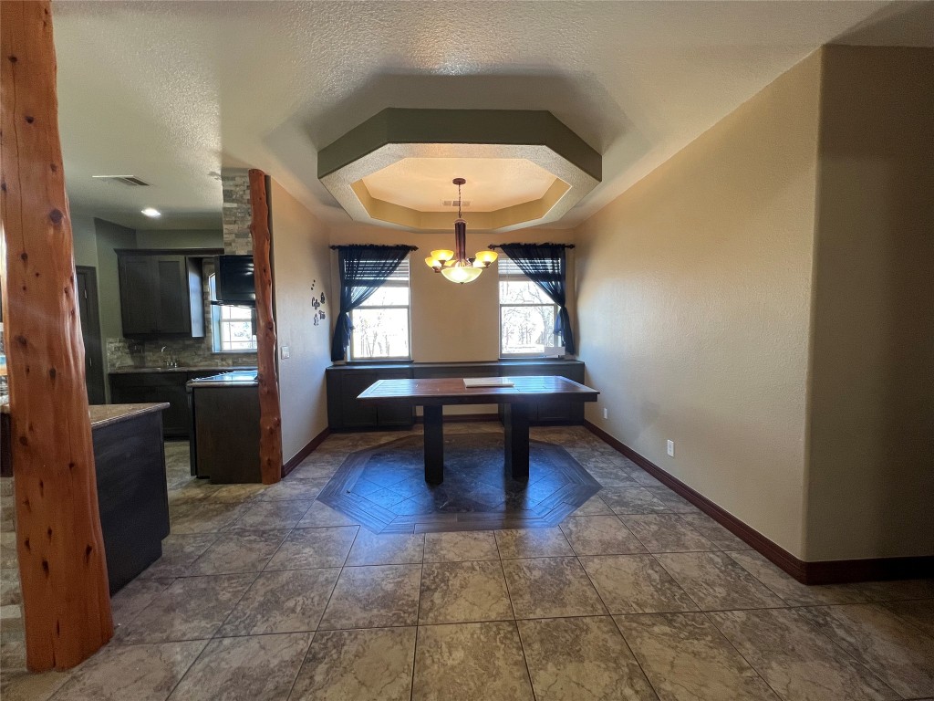 665 Wilson Road Red Rock, TX 78662 - Photo 16 of 34 Unfurnished dining area with a textured ceiling, a chandelier, and a tray ceiling