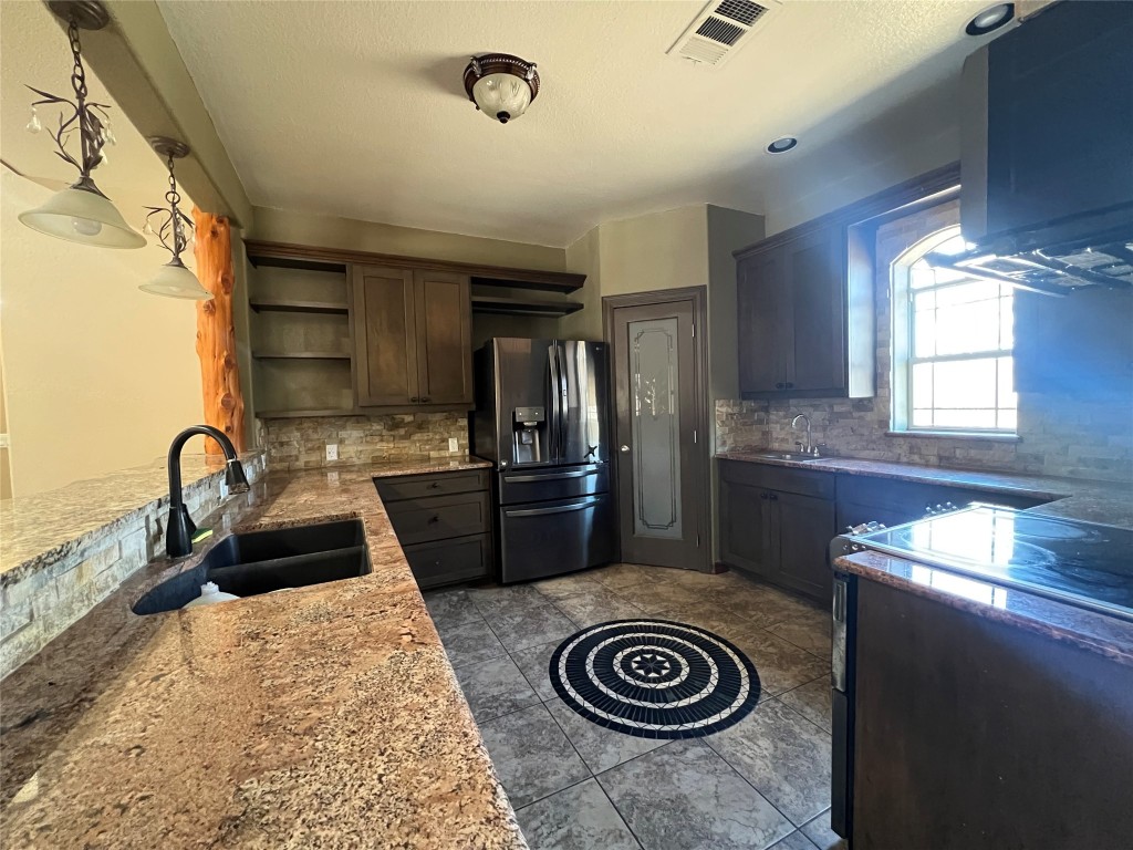 665 Wilson Road Red Rock, TX 78662 - Photo 18 of 34 Kitchen featuring open shelves, black fridge with ice dispenser, electric range oven, and light stone countertops