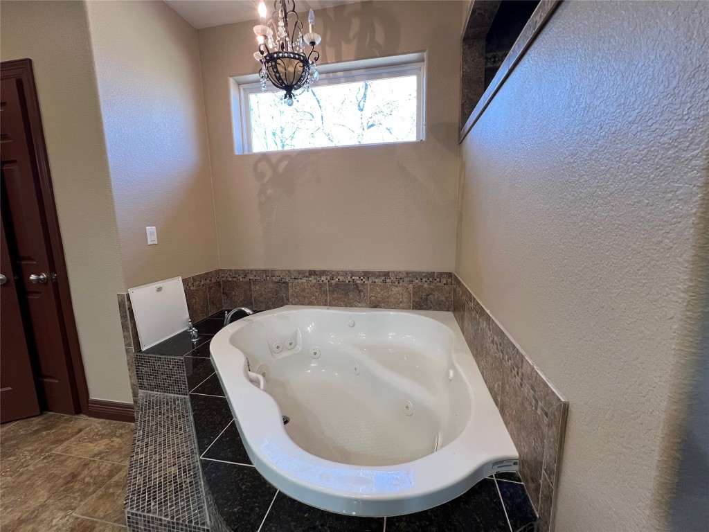 665 Wilson Road Red Rock, TX 78662 - Photo 23 of 34 Full bathroom with a tub with jets, a textured wall, and a chandelier