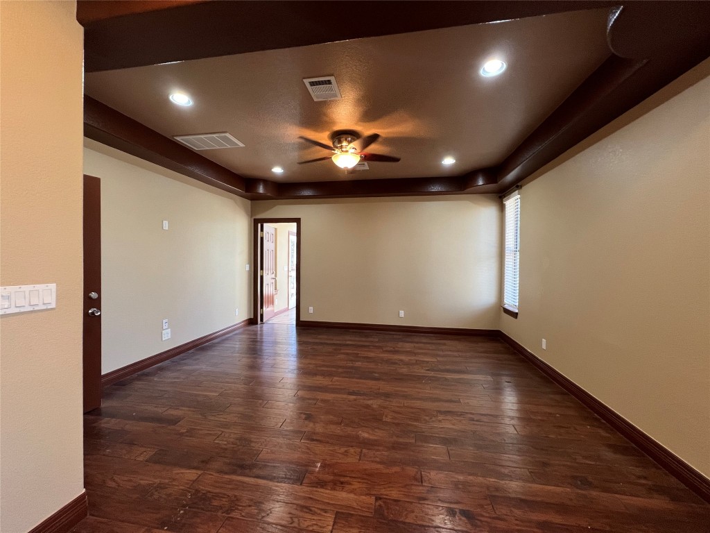 665 Wilson Road Red Rock, TX 78662 - Photo 24 of 34 Unfurnished room with dark wood finished floors, recessed lighting, a ceiling fan, and a tray ceiling