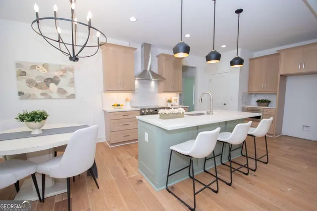 a kitchen with kitchen island stainless steel appliances a table chairs sink and wooden floor