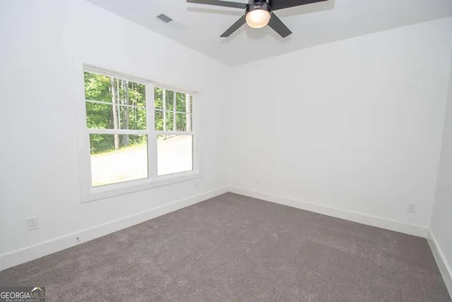 an empty room with a window and a fan