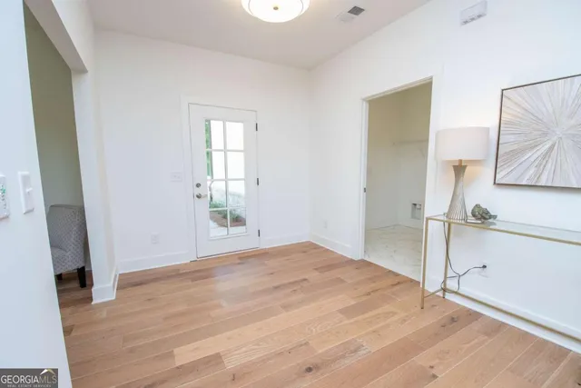 a view of an empty room with window and wooden floor