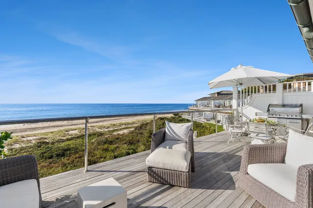 a view of a patio with couches and table and chairs under an umbrella with wooden floor
