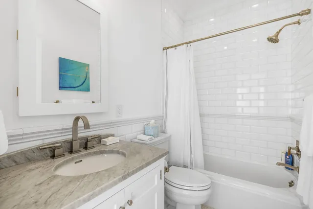 a bathroom with a granite countertop sink a toilet and shower