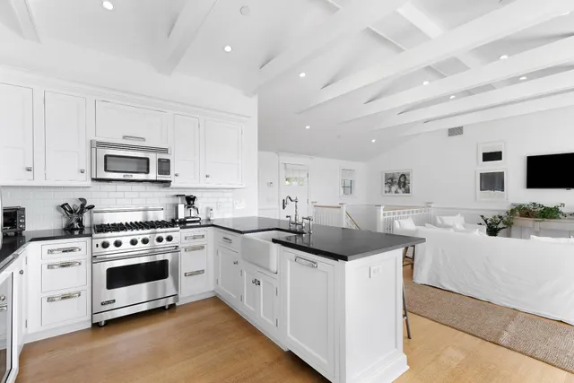 a kitchen with stainless steel appliances granite countertop white cabinets a sink a stove a microwave and a refrigerator