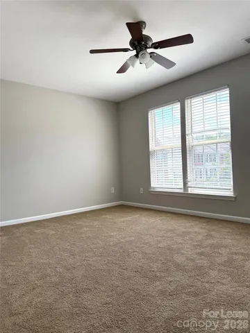 an empty room with a chandelier fan and windows