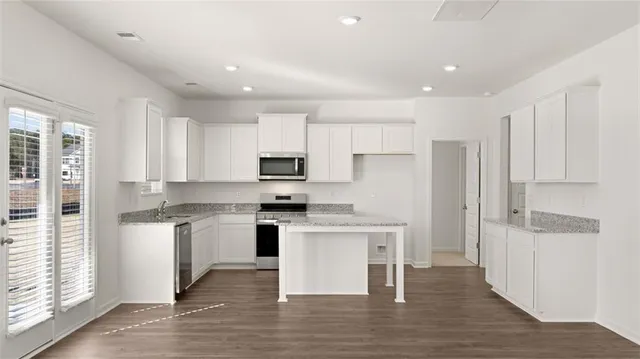 a kitchen with stainless steel appliances a stove top oven a refrigerator a center island and cabinets