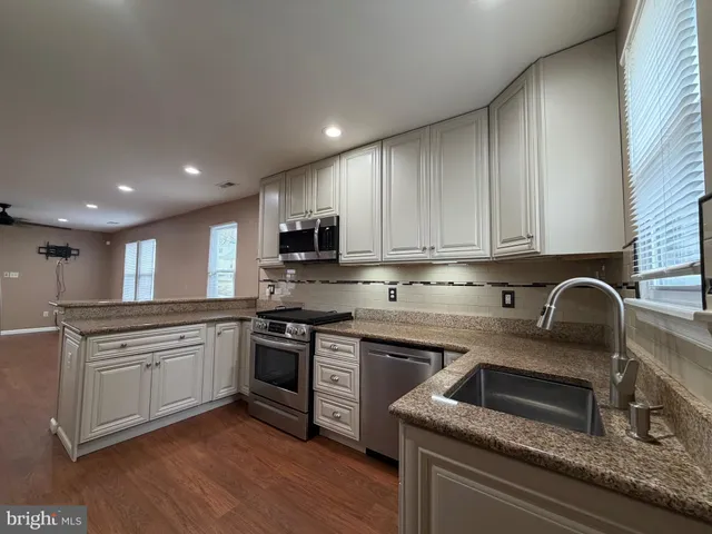 a kitchen with stainless steel appliances granite countertop a stove sink and cabinets