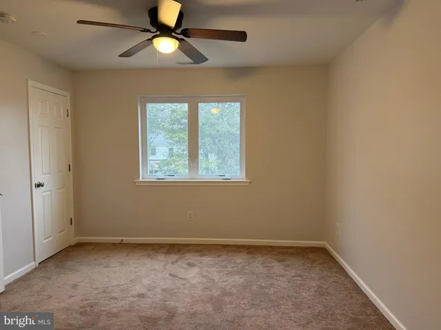 an empty room with a window and a fan