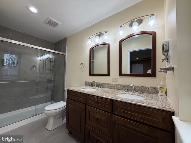 a bathroom with a double vanity sink toilet and a mirror
