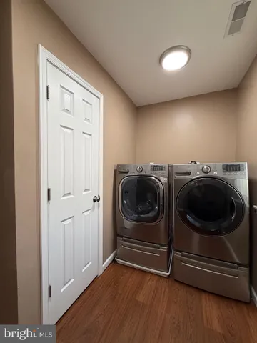 a utility room with wooden floor washer and dryer