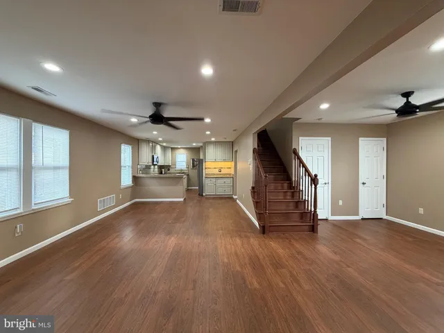 a view of an empty room with wooden floor stairs and a window