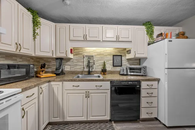 a kitchen with granite countertop white cabinets and white appliances