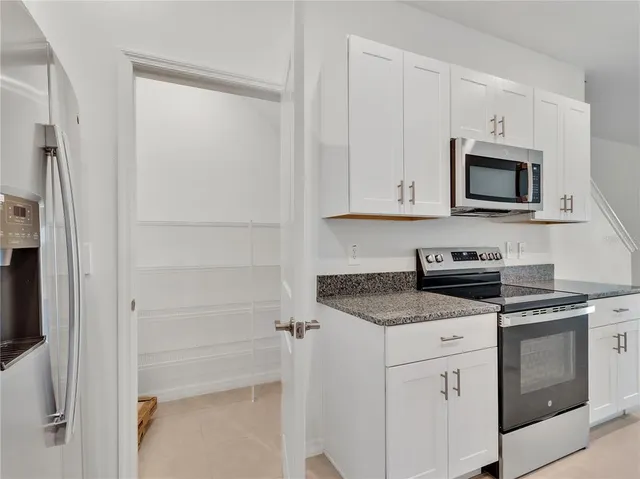 a kitchen with stainless steel appliances granite countertop white cabinets and a stove a refrigerator with white countertops