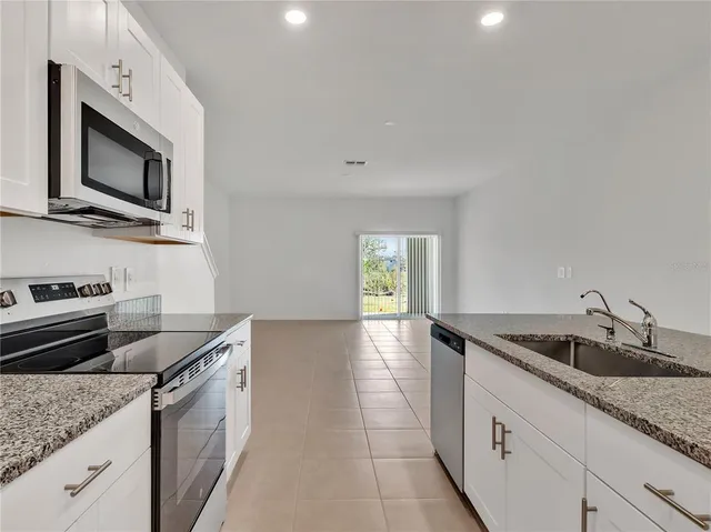 a kitchen with granite countertop a sink and stainless steel appliances