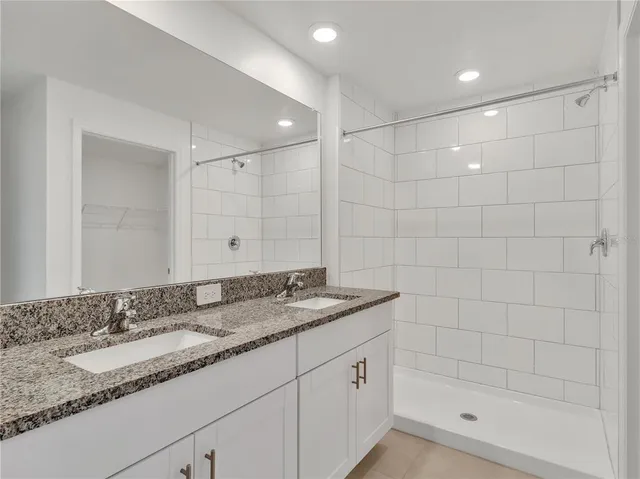 a bathroom with a granite countertop bathtub shower sink and vanity