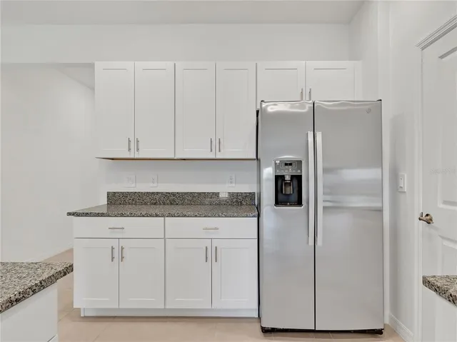 a kitchen with white cabinets and refrigerator